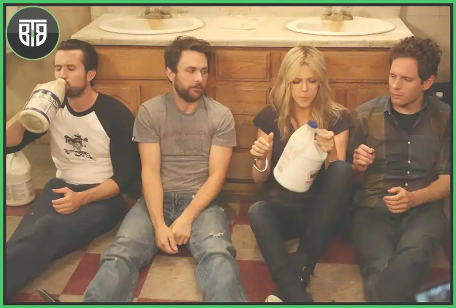 three men and 1 girl is sitting on the washroom flour and are looking something in It's Always Sunny in Philadeplhia, watch binge 